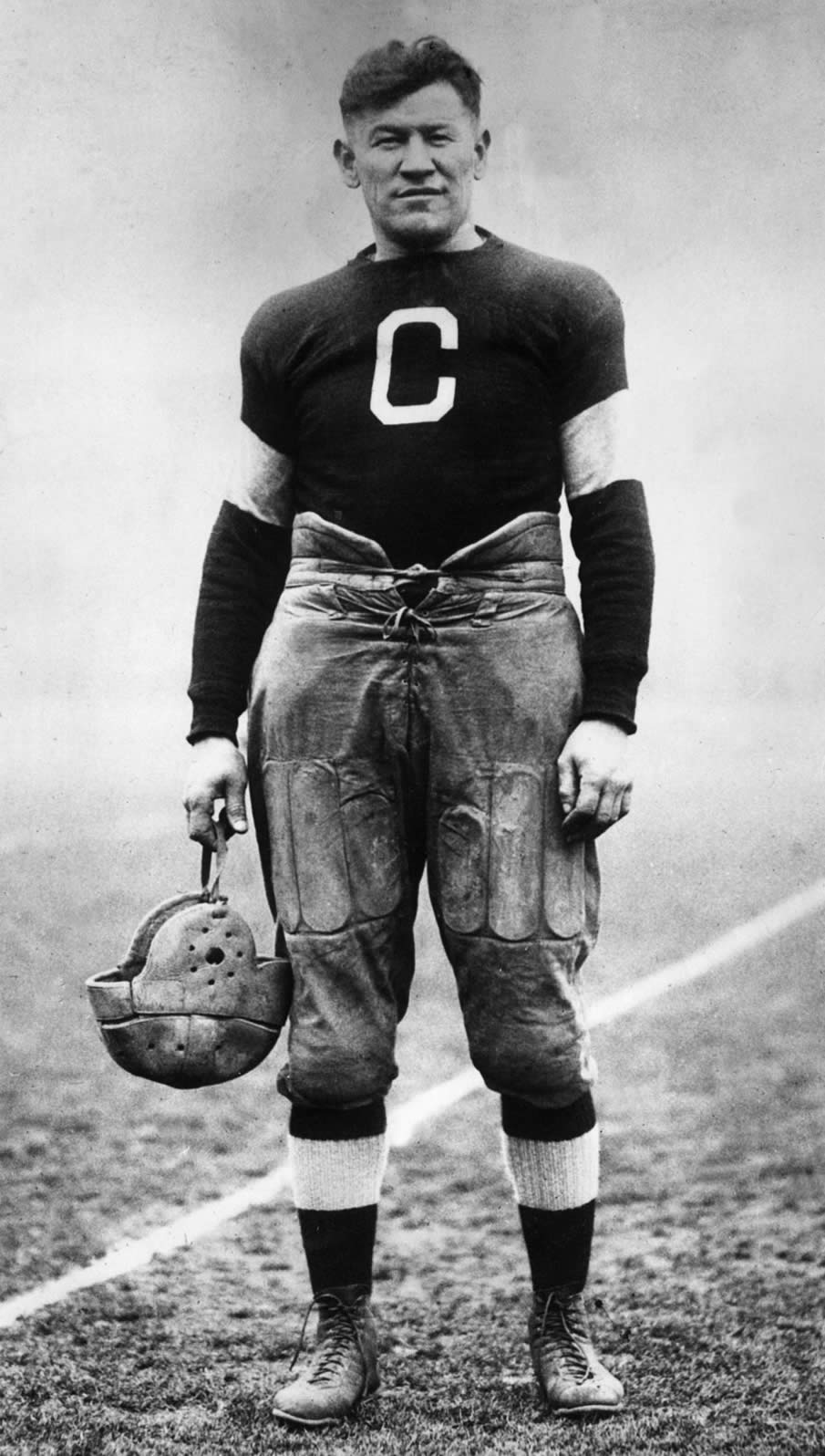 circa 1915:  American athlete Jim Thorpe posing in a football uniform on a field. 