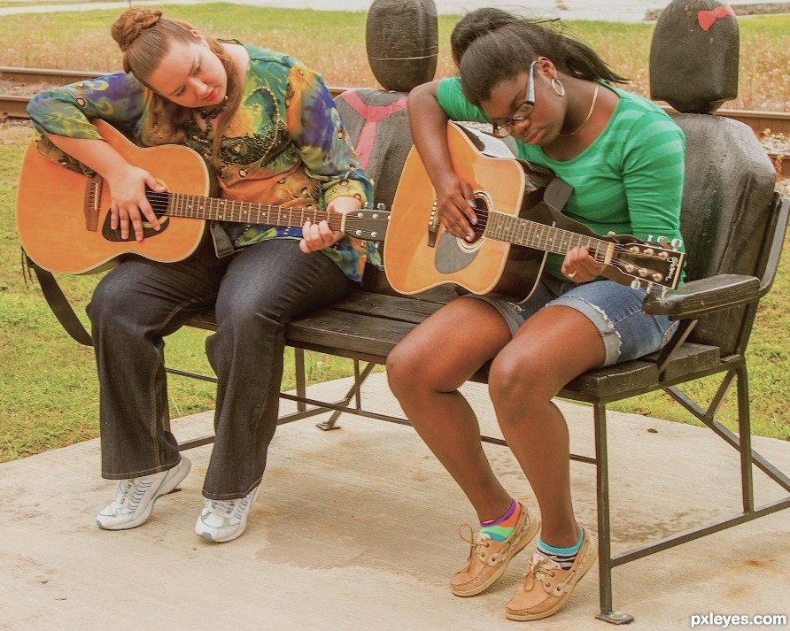 Two girls playing guitar in the park