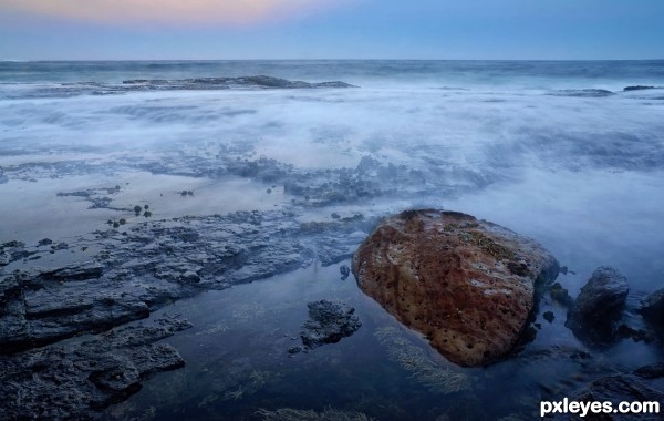 Wave washing over rocks at sunset