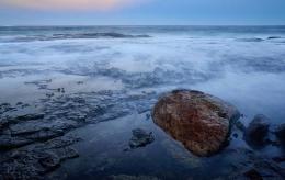 Wave washing over rocks at sunset